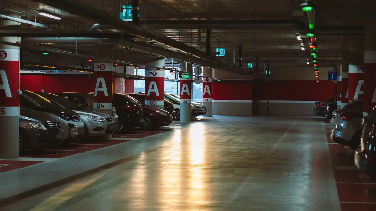 Interno di un'autorimessa multipiano con auto parcheggiate e colonne numerate