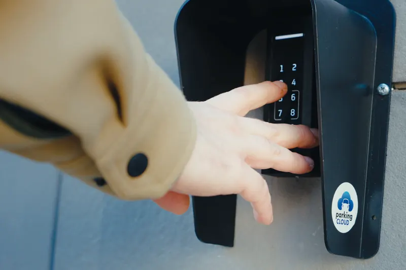 Mano che digita il codice sul tastierino di accesso Parking Cloud all'ingresso di un parcheggio